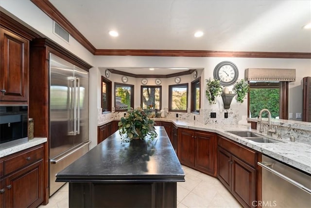 kitchen with a kitchen island, appliances with stainless steel finishes, sink, decorative backsplash, and light tile patterned floors