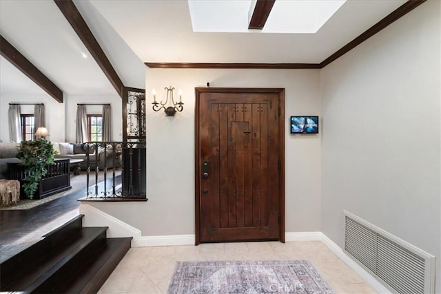 tiled foyer featuring beamed ceiling and a skylight