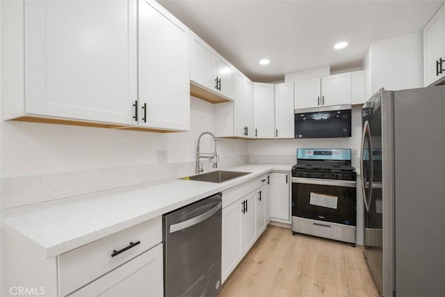 kitchen with sink, light hardwood / wood-style flooring, white cabinets, and appliances with stainless steel finishes