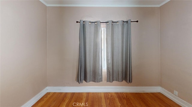 empty room with ornamental molding and hardwood / wood-style floors