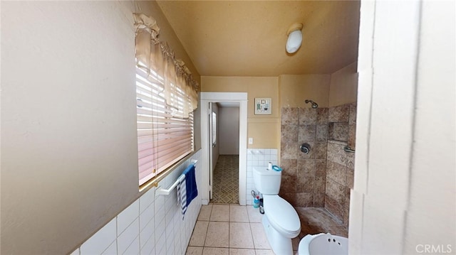 bathroom with tiled shower, tile walls, tile patterned floors, and toilet