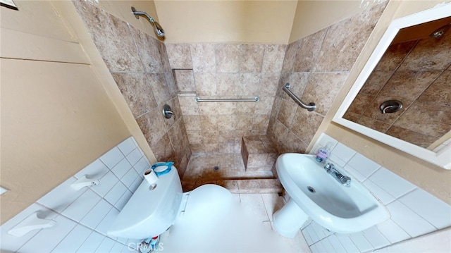 bathroom featuring tiled shower, toilet, and sink