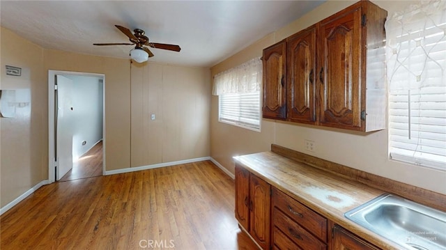 kitchen with ceiling fan, sink, and light wood-type flooring