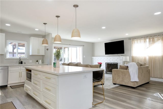 kitchen featuring stainless steel appliances, sink, white cabinets, and decorative light fixtures