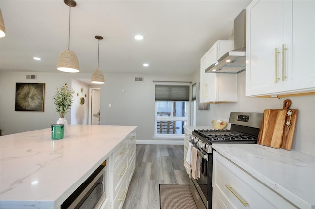 kitchen featuring wall chimney exhaust hood, appliances with stainless steel finishes, pendant lighting, light stone countertops, and white cabinets