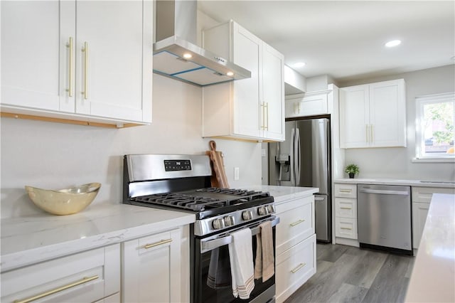 kitchen featuring white cabinets, hardwood / wood-style flooring, wall chimney exhaust hood, and appliances with stainless steel finishes