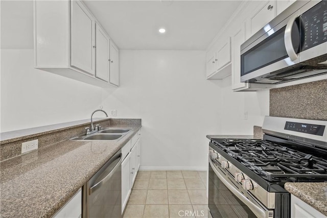 kitchen with sink, white cabinetry, dark stone counters, light tile patterned floors, and stainless steel appliances