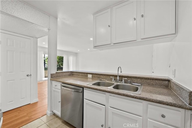 kitchen featuring white cabinetry, stainless steel dishwasher, light tile patterned flooring, and sink