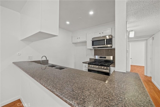 kitchen featuring white cabinetry, appliances with stainless steel finishes, sink, and light wood-type flooring