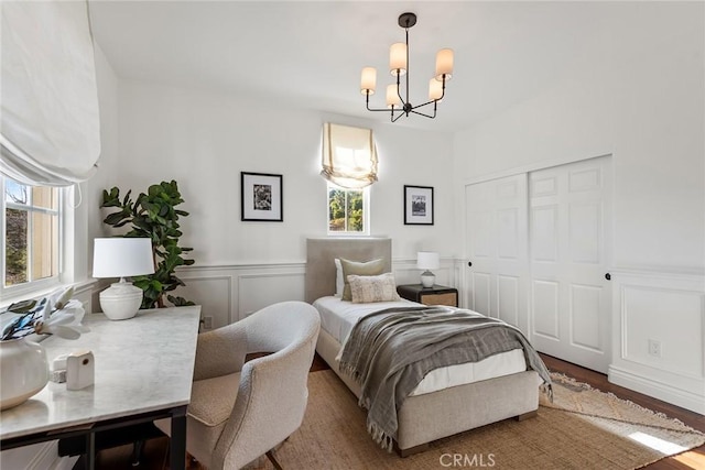 bedroom with an inviting chandelier, wood-type flooring, and a closet