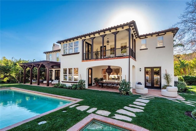 rear view of property with a balcony, a lawn, a pergola, ceiling fan, and a patio