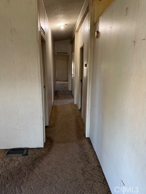 corridor with light colored carpet and a textured ceiling