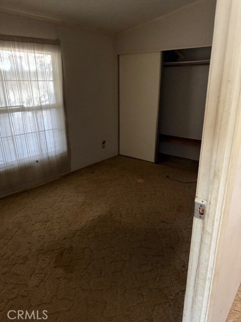 unfurnished bedroom featuring vaulted ceiling, a closet, and carpet