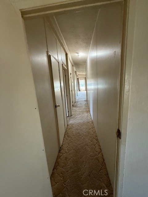 corridor with light colored carpet and a textured ceiling