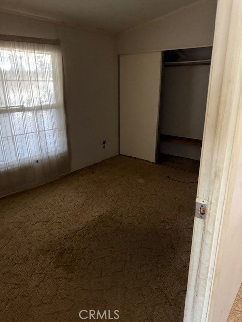 unfurnished bedroom featuring lofted ceiling, a closet, and carpet flooring