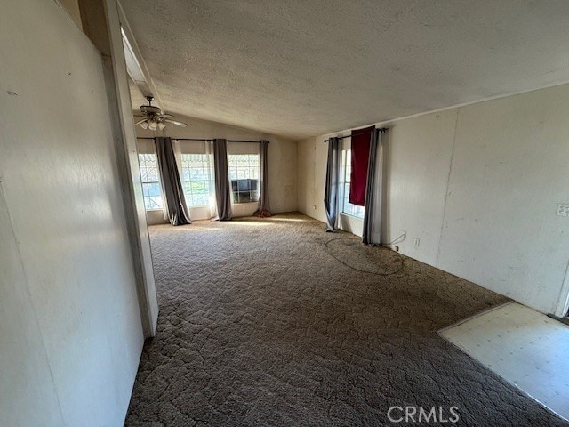 carpeted spare room featuring vaulted ceiling, ceiling fan, and a textured ceiling