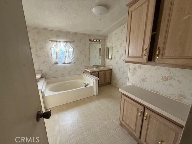 bathroom with vanity, a bath, and a textured ceiling