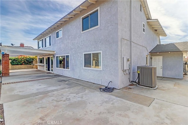 rear view of property with central AC unit, a pergola, and a patio area