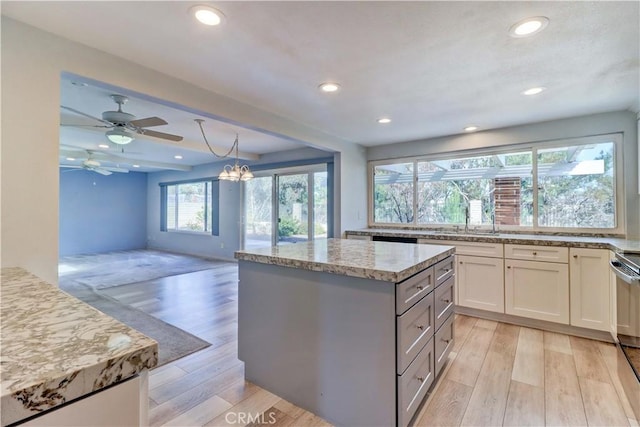 kitchen with pendant lighting, light stone countertops, light hardwood / wood-style floors, and white cabinets