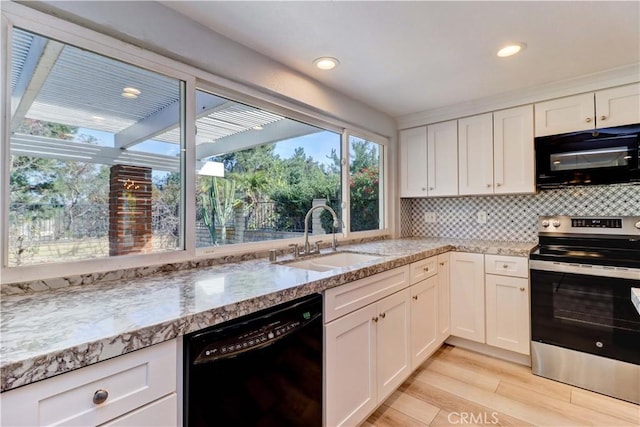 kitchen featuring sink, light hardwood / wood-style flooring, white cabinetry, tasteful backsplash, and black appliances