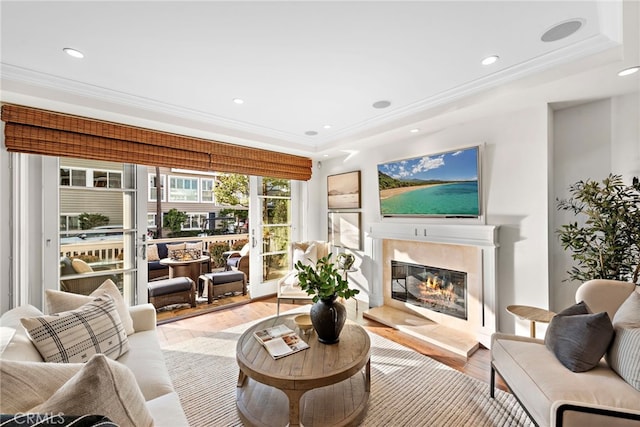 living room with a premium fireplace, ornamental molding, and light hardwood / wood-style floors