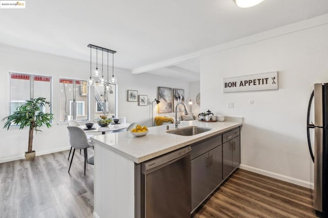 kitchen featuring pendant lighting, sink, dark hardwood / wood-style flooring, kitchen peninsula, and stainless steel appliances