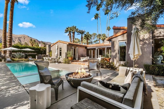 exterior space featuring a mountain view, a patio, and an outdoor living space with a fire pit