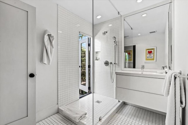 bathroom with tile patterned flooring, vanity, and tiled shower