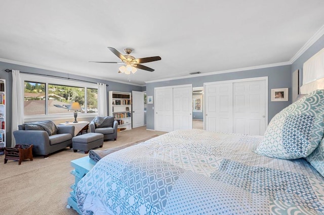 bedroom featuring light carpet, two closets, crown molding, and ceiling fan