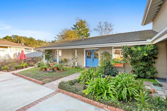 ranch-style home with a tile roof, fence, and stucco siding