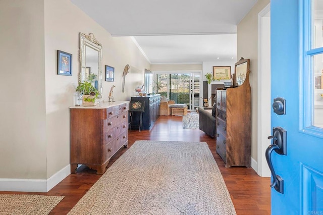 foyer entrance with dark wood-type flooring, crown molding, and baseboards