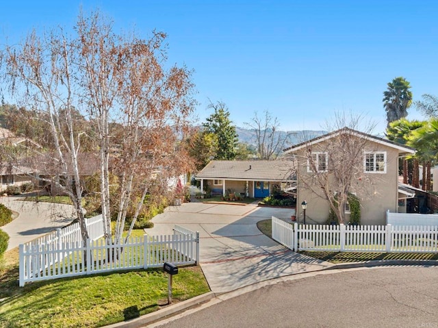 split level home featuring a fenced front yard, concrete driveway, and stucco siding