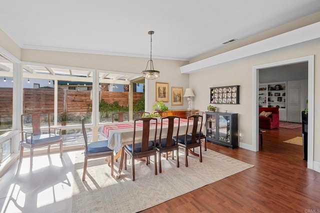 dining room with visible vents, crown molding, baseboards, and wood finished floors