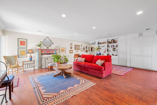 living area with recessed lighting, wood finished floors, visible vents, built in features, and crown molding