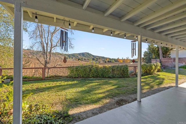 view of yard featuring fence, a mountain view, and a patio