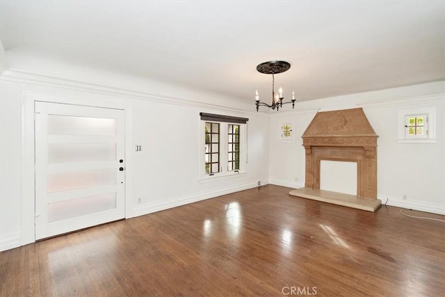 unfurnished living room featuring dark hardwood / wood-style floors, plenty of natural light, a fireplace, and a chandelier