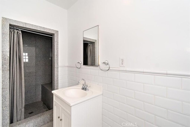 bathroom with vanity, tiled shower, and tile walls