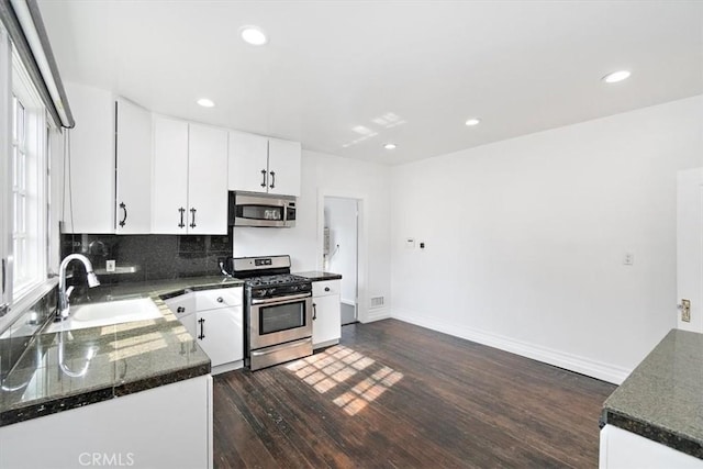 kitchen featuring dark wood-type flooring, sink, white cabinets, stainless steel appliances, and backsplash