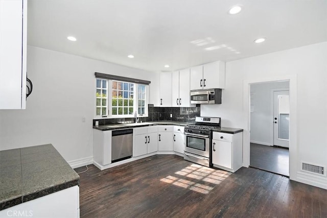 kitchen featuring white cabinetry, sink, dark hardwood / wood-style flooring, decorative backsplash, and stainless steel appliances