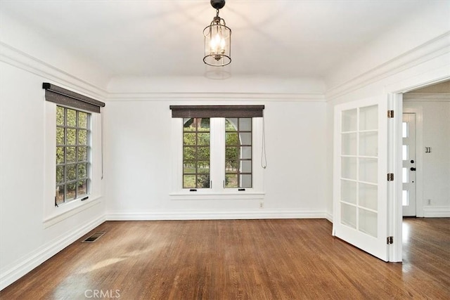 spare room featuring an inviting chandelier and hardwood / wood-style floors