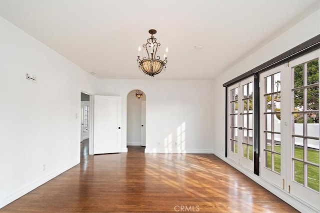 empty room featuring an inviting chandelier and dark hardwood / wood-style floors