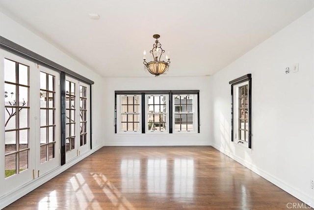 spare room with hardwood / wood-style floors and a chandelier