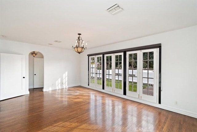 empty room featuring hardwood / wood-style flooring and a chandelier