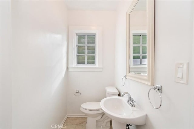 bathroom with a healthy amount of sunlight, sink, and toilet