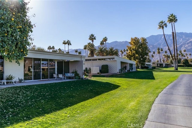 back of property with a mountain view and a lawn