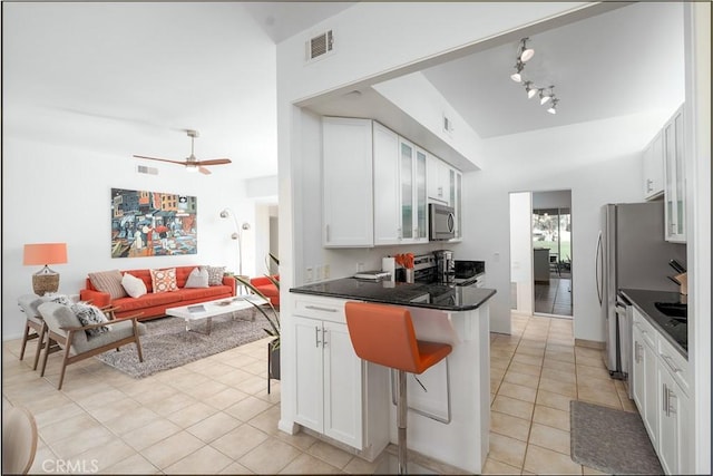 kitchen with a breakfast bar area, ceiling fan, white cabinetry, stainless steel appliances, and light tile patterned flooring