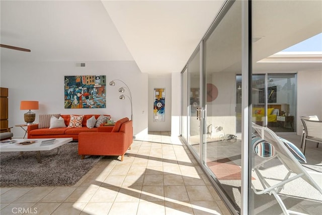 tiled living room featuring ceiling fan and a wall of windows