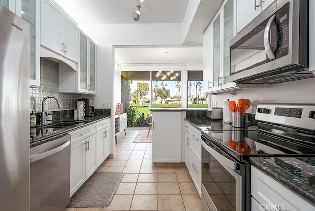 kitchen with dark stone countertops, light tile patterned floors, white cabinetry, and appliances with stainless steel finishes