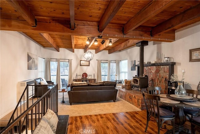 living room with hardwood / wood-style floors, wood ceiling, beamed ceiling, and a wood stove