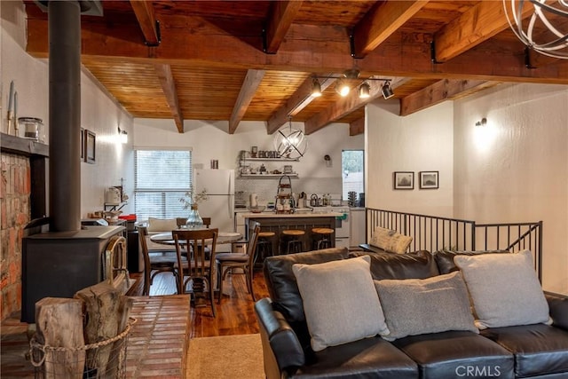 living room with rail lighting, a wood stove, hardwood / wood-style flooring, wood ceiling, and beam ceiling